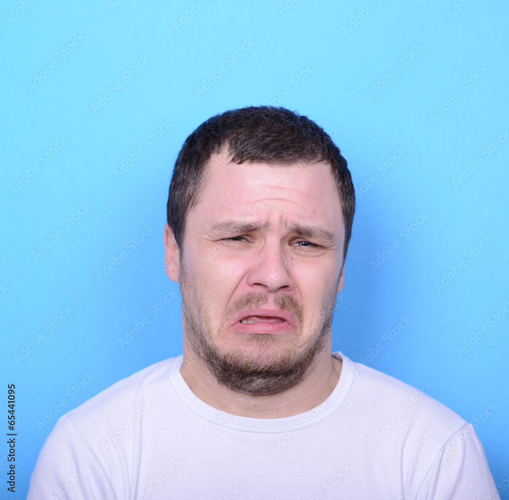 Portrait of man with dusgusted gesture against blue background Portrait of man with dusgusted gesture against blue background