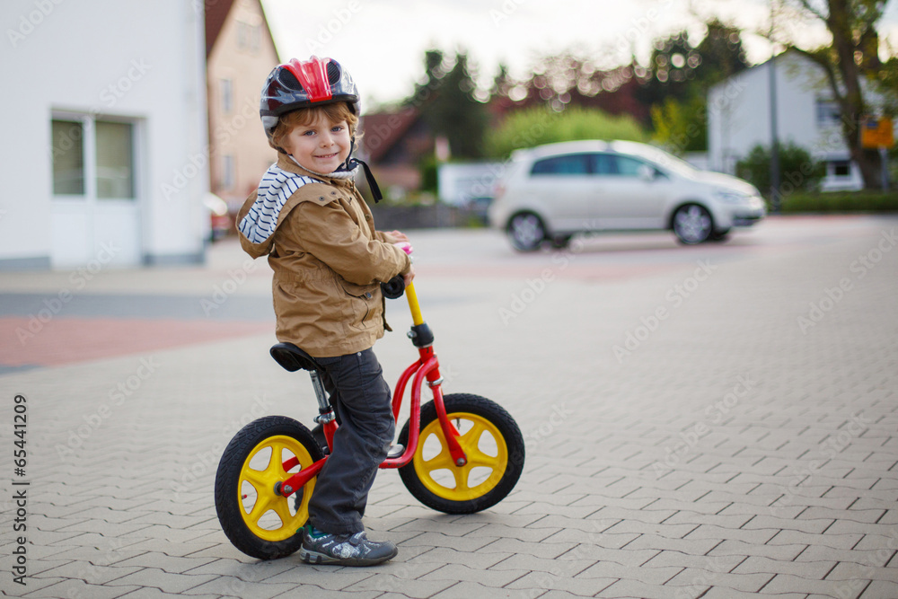 Fototapeta premium Little toddler boy learning to ride on his first bike
