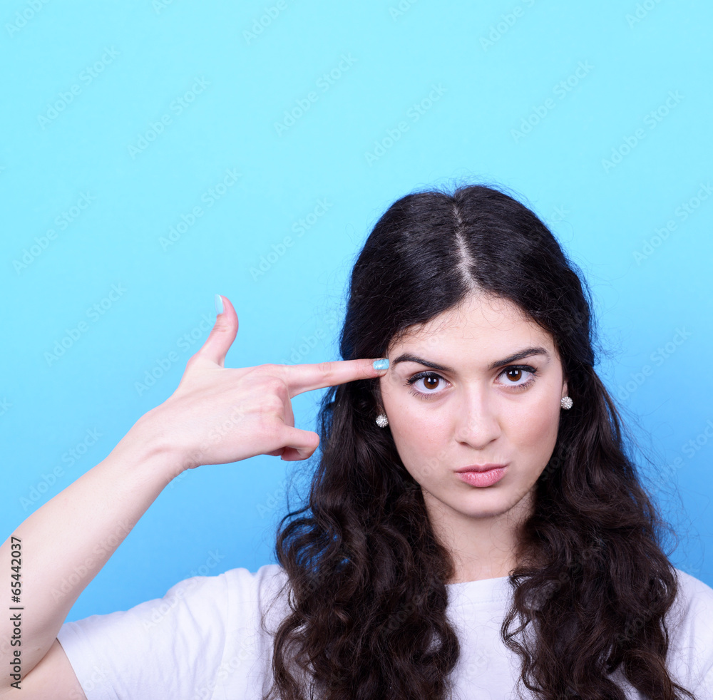 Portrait of angry girl pointing hand made pistol against blue ba Portrait of angry girl pointing hand made pistol against blue ba