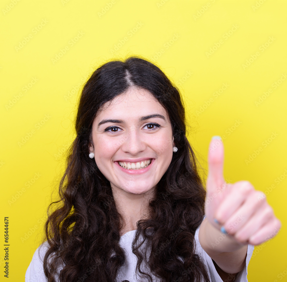 Portrait of happy woman with thumbs up against yellow background Portrait of happy woman with thumbs up against yellow background