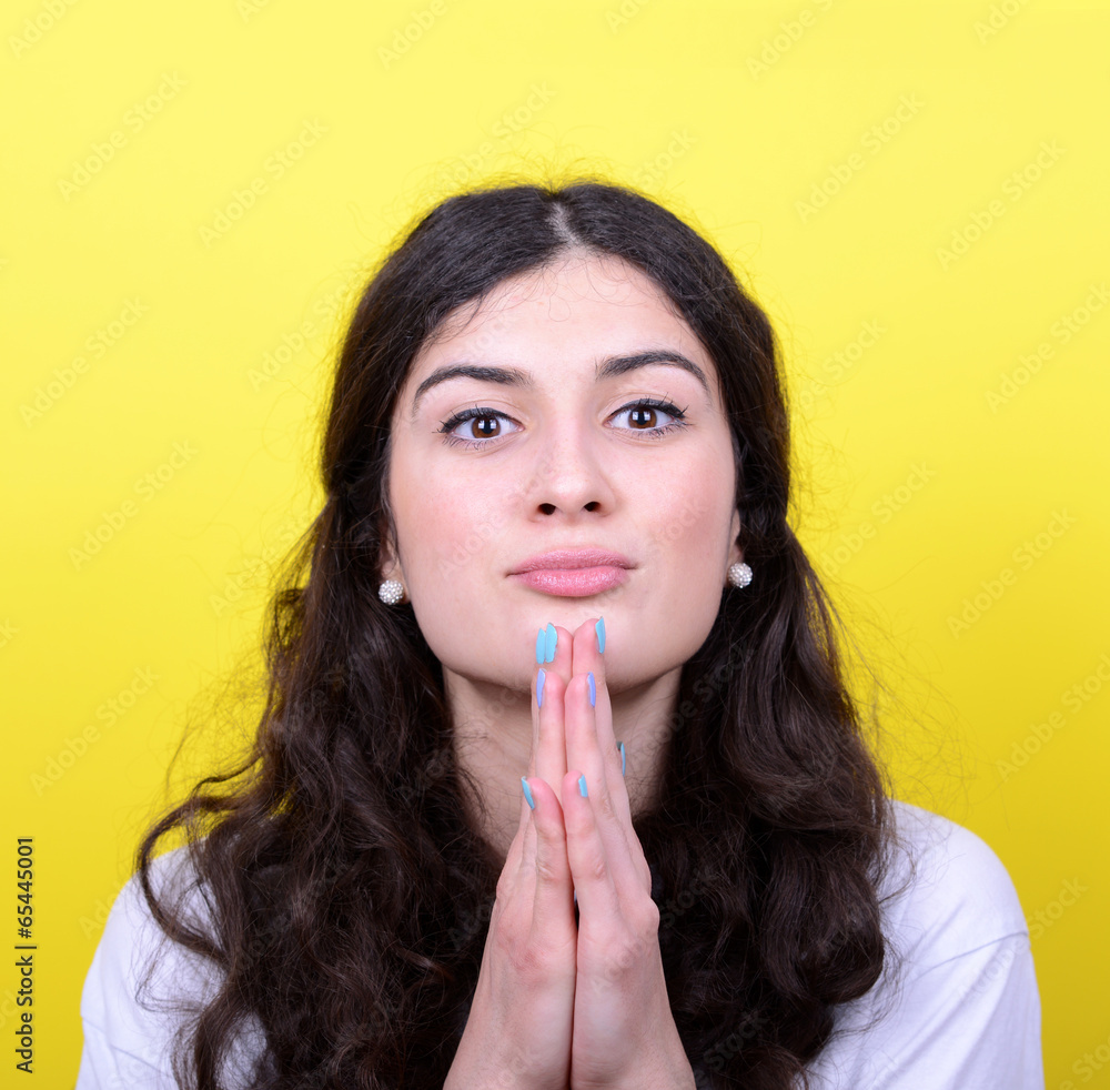 Portrait of woman praying against yellow background Portrait of woman praying against yellow background