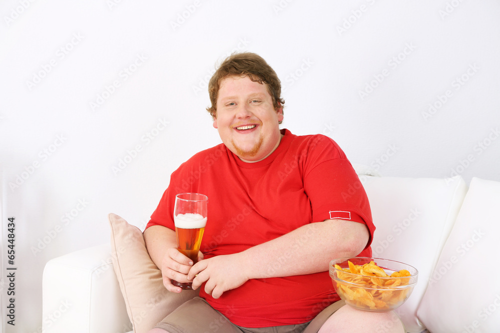 Lazy overweight male sitting on couch and watching television Lazy overweight male sitting on couch and watching television