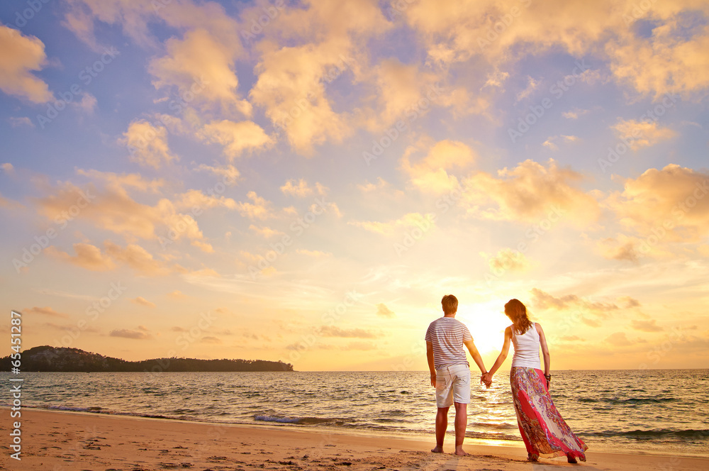 Fototapeta premium young couple stands at the sea beach looking at sunset
