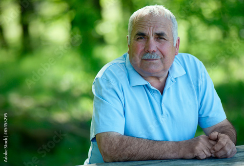 Elderly man sitting outdoors smiling at the camera