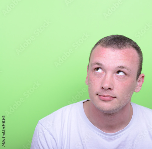 Portrait of man thinking and looking up against green background