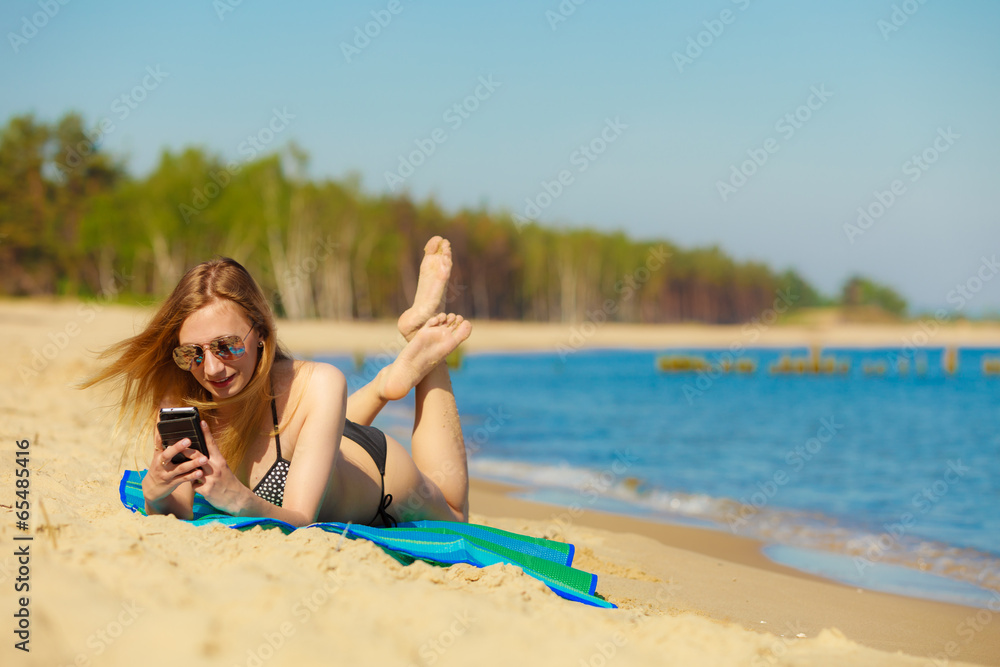 Summer vacation Girl with phone tanning on beach Summer vacation Girl with phone tanning on beach