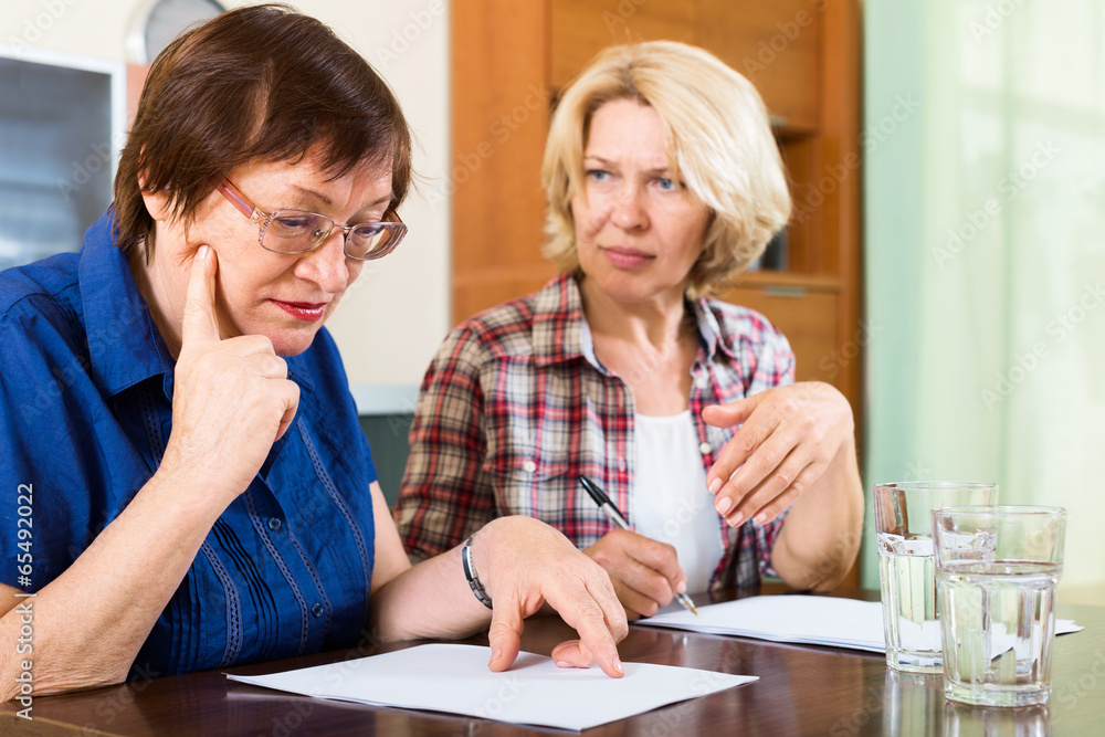 Fototapeta premium Two sad mature women looking documents