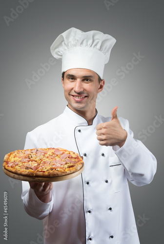 Smiling chef with fresh pizza showing thumbs up photo