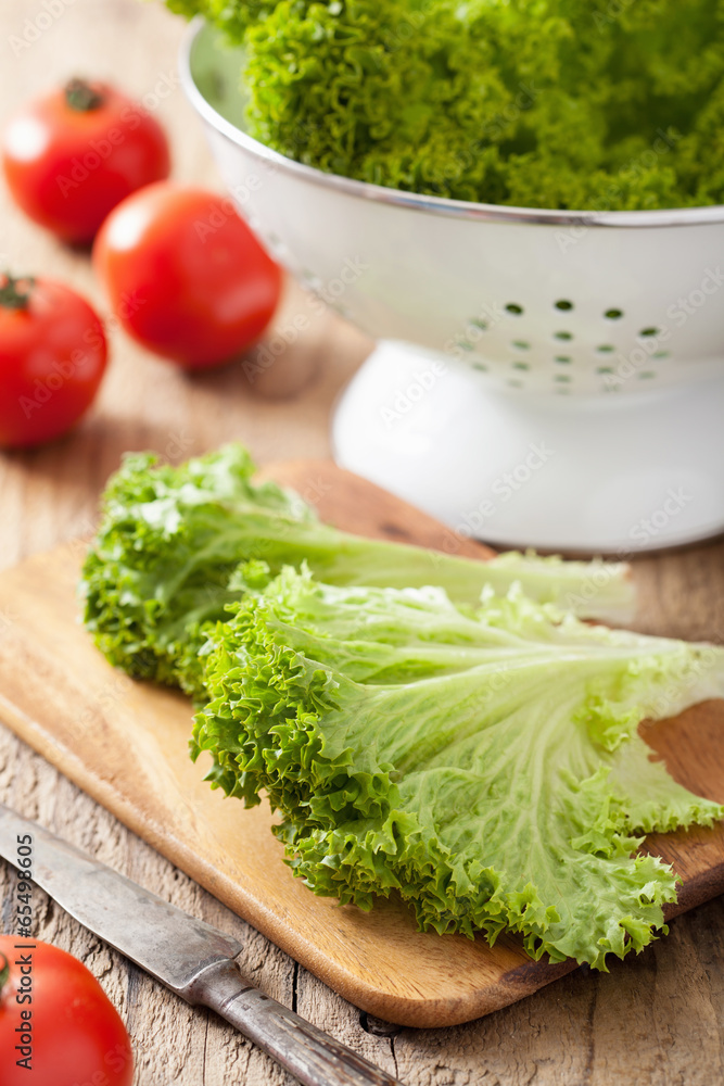 fresh lollo leaves and tomatoes on chopping board for salad fresh lollo leaves and tomatoes on chopping board for salad