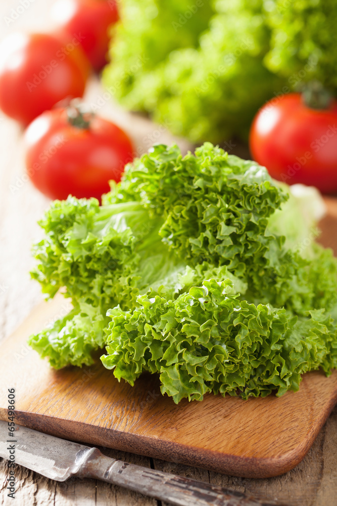 fresh lollo leaves and tomatoes on chopping board for salad fresh lollo leaves and tomatoes on chopping board for salad