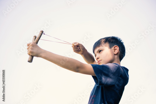 Child aiming with sling outdoors portrait. photo