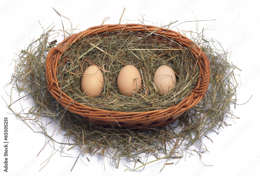 Three organic eggs in a wicker basket on the hay Three organic eggs in a wicker basket on the hay