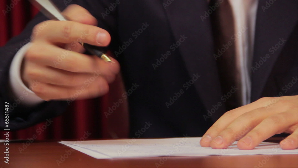 Male boss putting his signature on papers, signing an agreement Male boss putting his signature on papers, signing an agreement