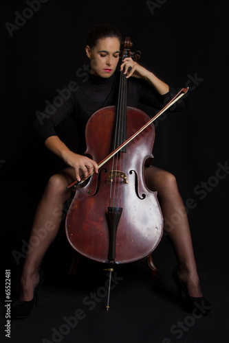 Beautiful woman playnig a cello with selective light and black d photo