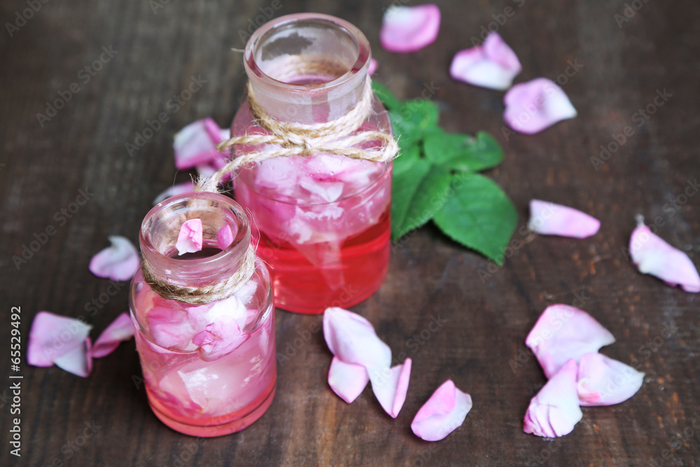 Rose oil in bottles on color wooden background Rose oil in bottles on color wooden background