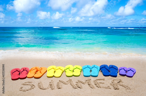 Sign "Summer" and color flip flops on sandy beach