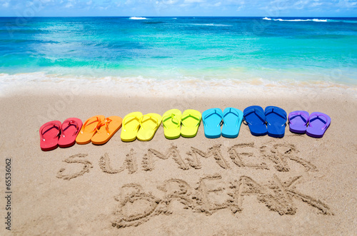 Sign "Summer break" and color flip flops on sandy beach
