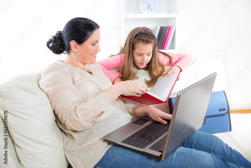 Mother and daughter using laptop together on sofa at home Mother and daughter using laptop together on sofa at home