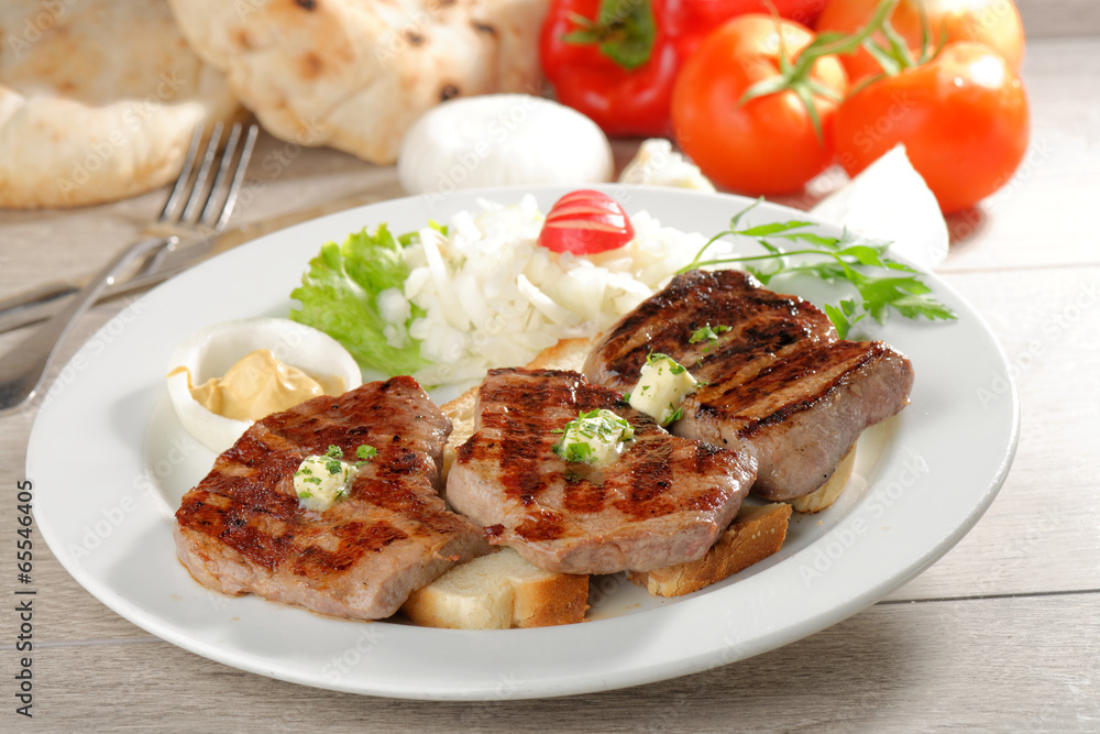 Grilled steaks on toast bread, served with onion and vegetable Grilled steaks on toast bread, served with onion and vegetable