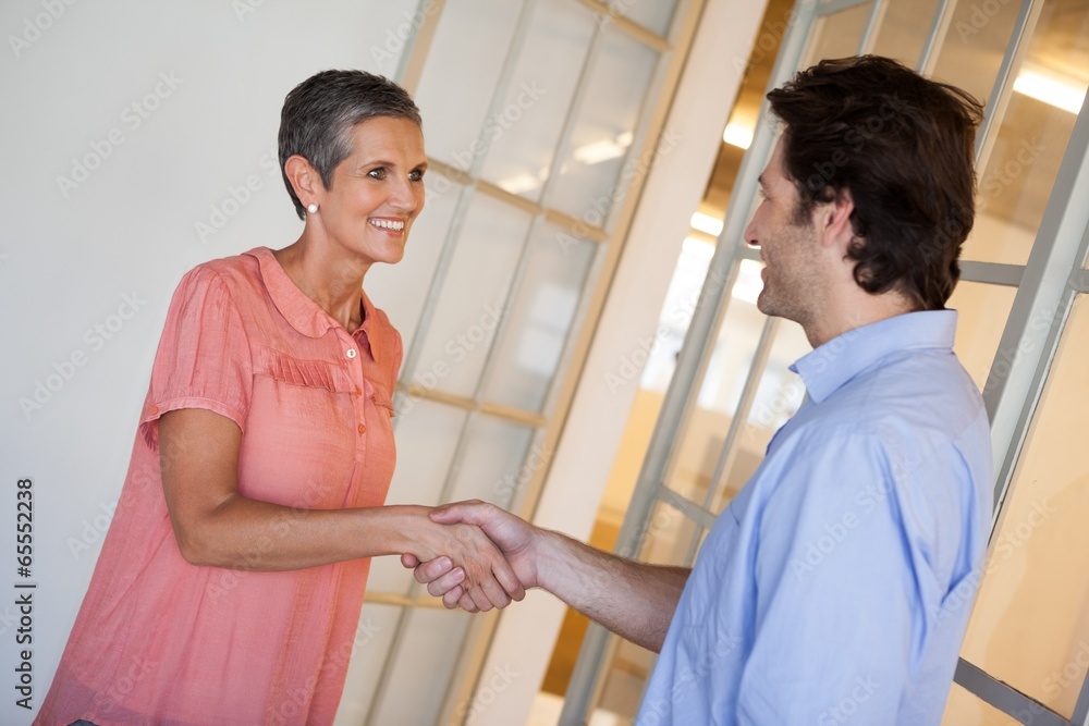 Obraz premium Casual smiling business people shaking hands