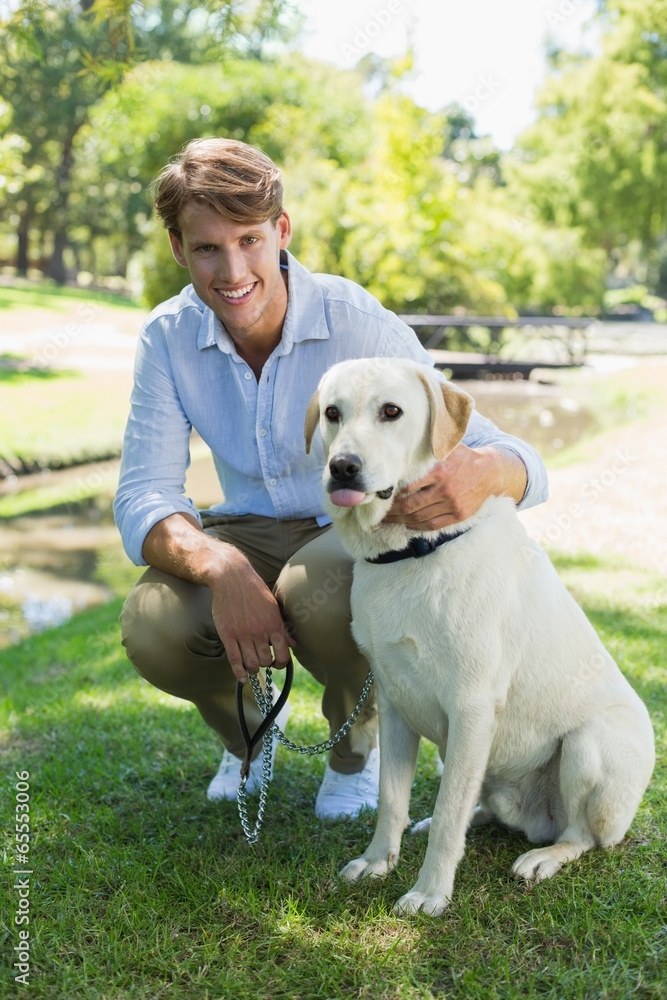 Handsome man with his labrador in the park smiling at camera Handsome man with his labrador in the park smiling at camera