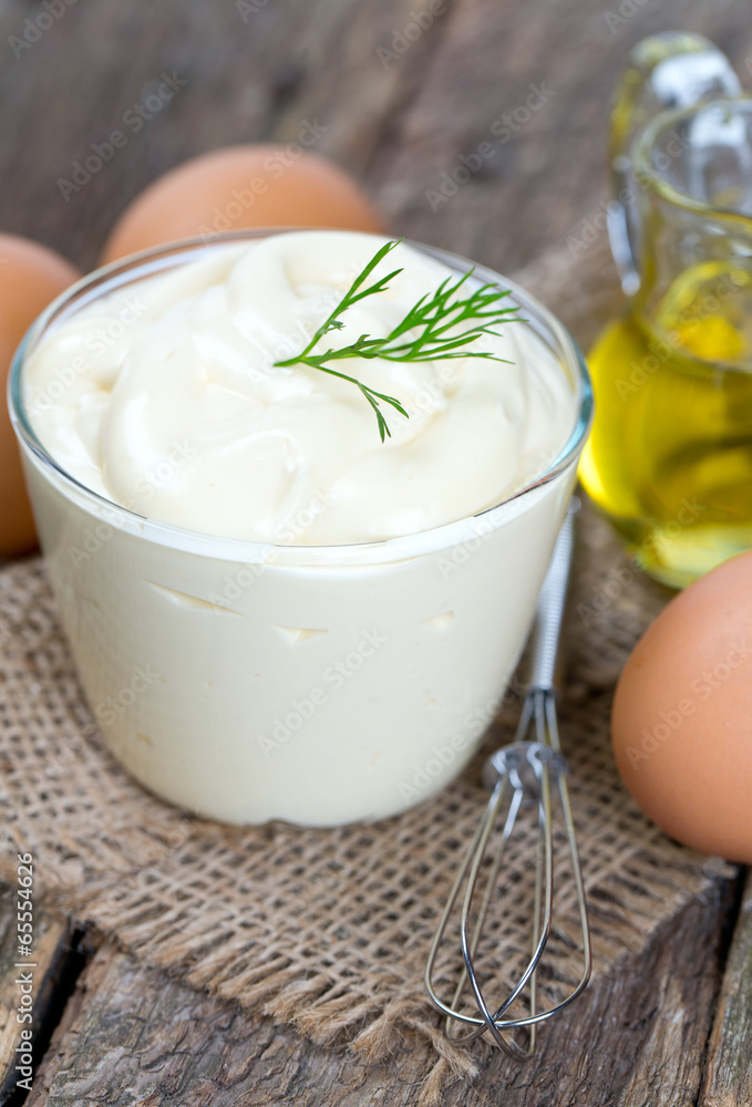 Mayonnaise in bowl with egg and olive oil on an old wooden table Mayonnaise in bowl with egg and olive oil on an old wooden table