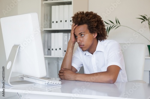 Casual stressed businessman looking at his computer