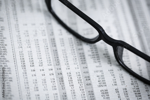 closeup glasses on financial newspaper with pen