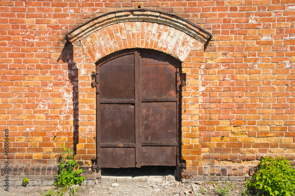 old rusty iron gate in the brick wall