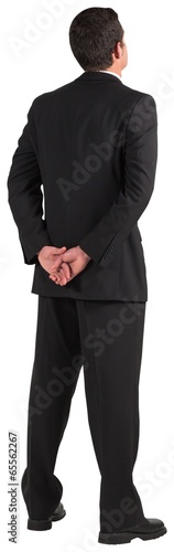 Businessman standing and looking with hands behind back