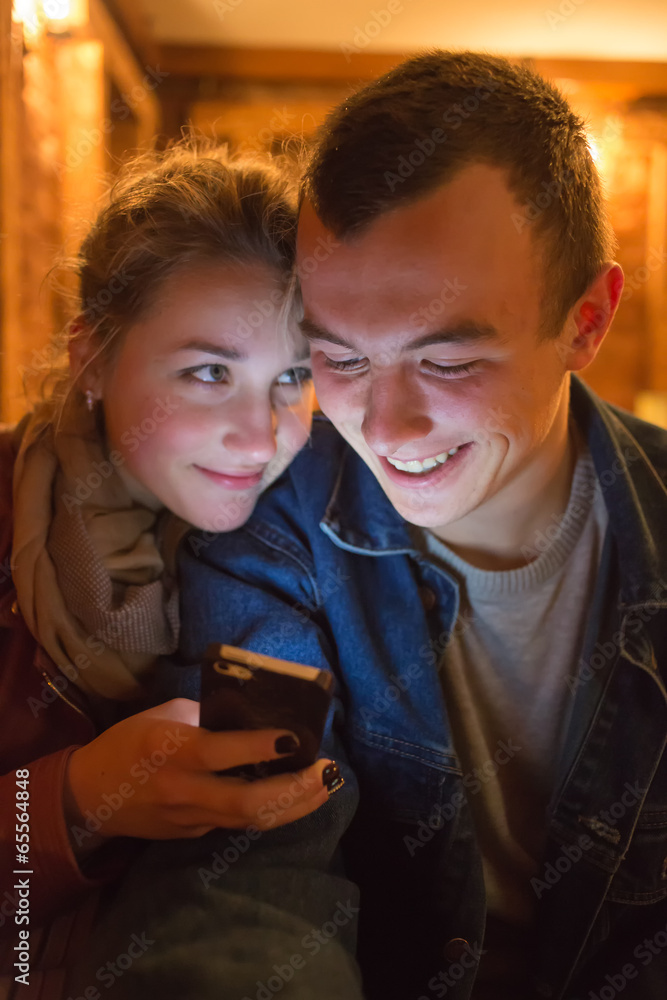 Fototapeta premium The young man and the girl look cellular telephon