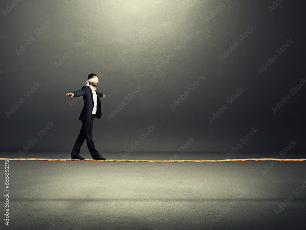 businessman balancing on the rope over dark businessman balancing on the rope over dark