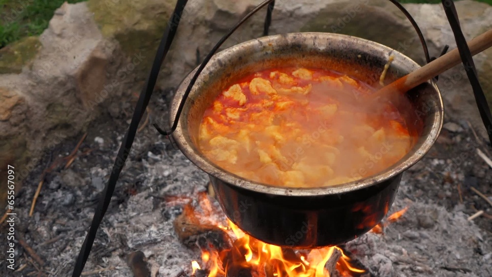 Stirring Hungarian paprika potatoes with noodles on a campfire Stirring Hungarian paprika potatoes with noodles on a campfire