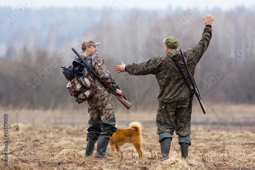 two hunters and dog on the field