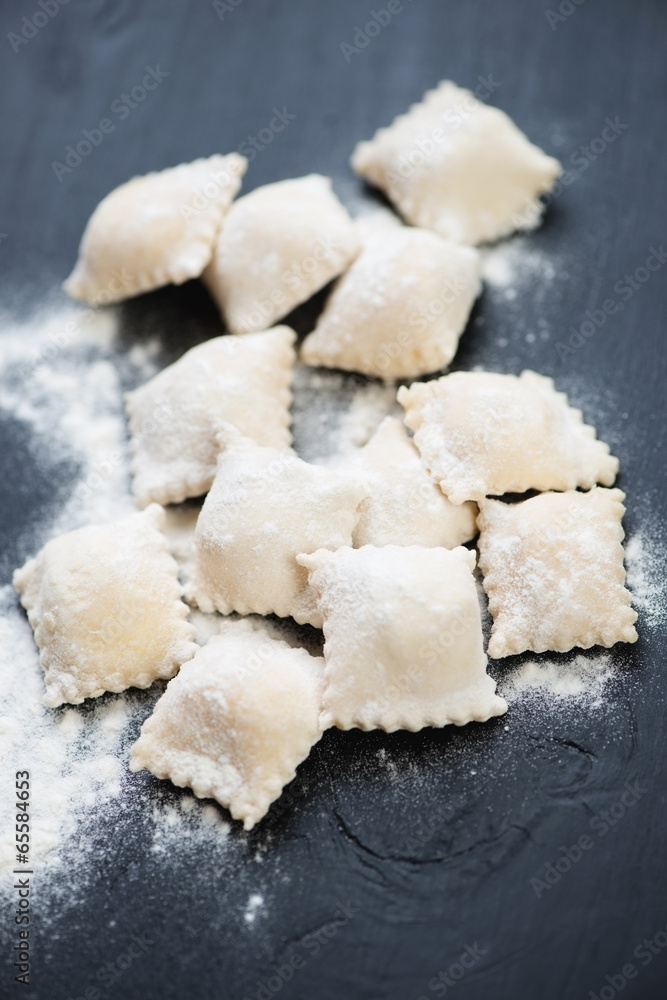 Raw square ravioli with mozzarella over black wooden background Raw square ravioli with mozzarella over black wooden background