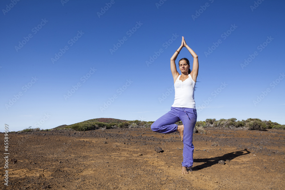 Young woman practicing tree yoga pose outdoor on a desert mounta Young woman practicing tree yoga pose outdoor on a desert mounta