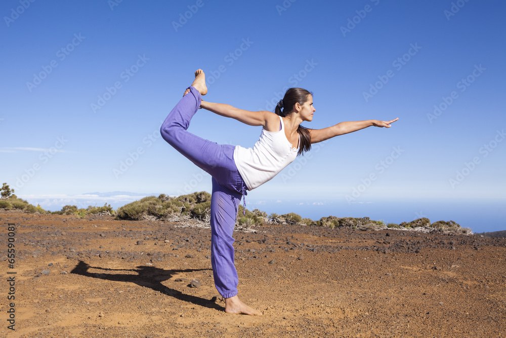 Young attractive woman doing dancers yoga pose outdoors on a des Young attractive woman doing dancers yoga pose outdoors on a des