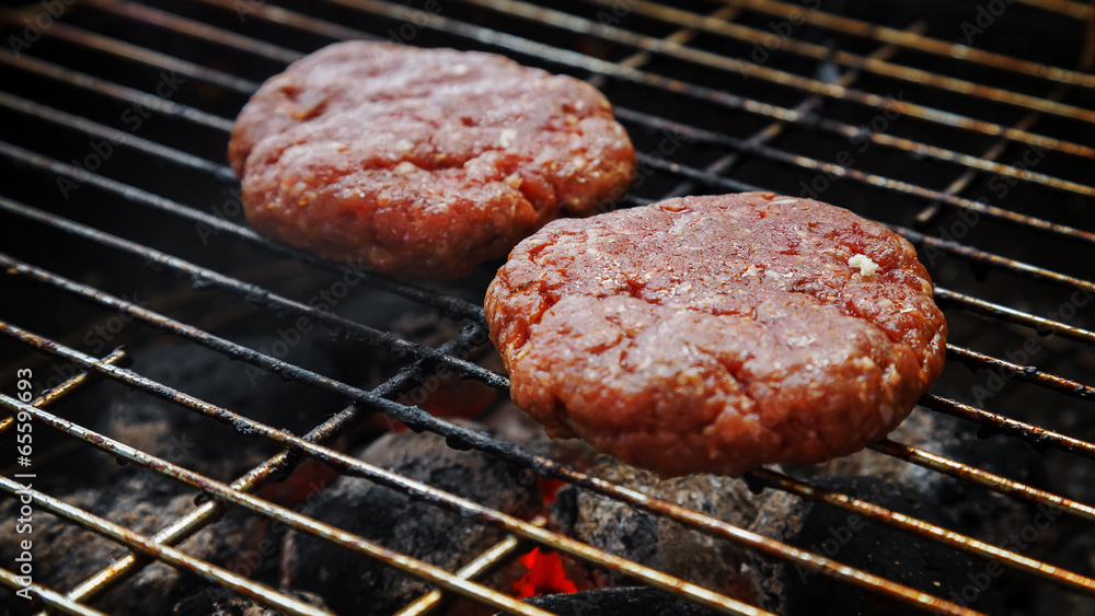 Raw beef burgers being broiled on the grill Raw beef burgers being broiled on the grill