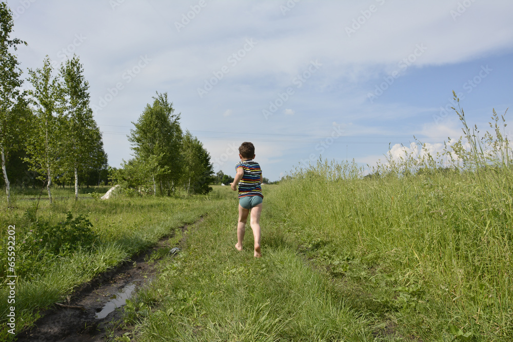 A village boy runs down the road in the field.