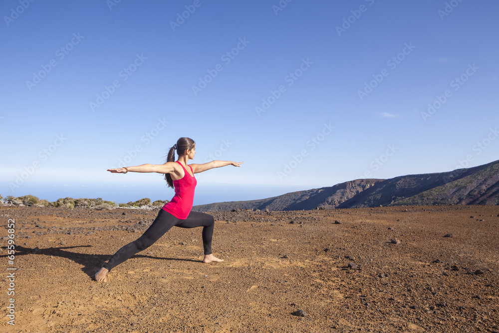Young woman practicing yoga warrior pose on a desert mountain Young woman practicing yoga warrior pose on a desert mountain
