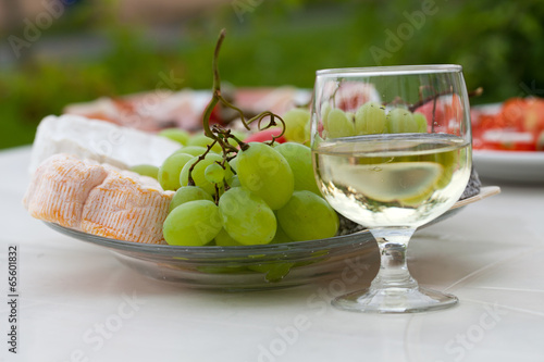 Various sorts of cheese, grapes and glass of the white wine