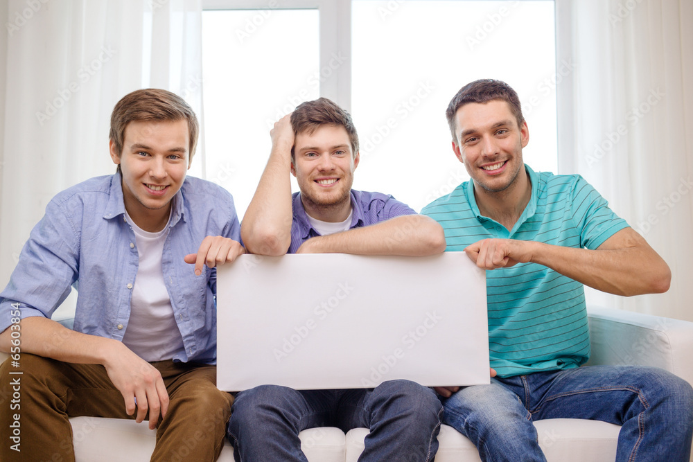 Fototapeta premium smiling male friends holding white blank board