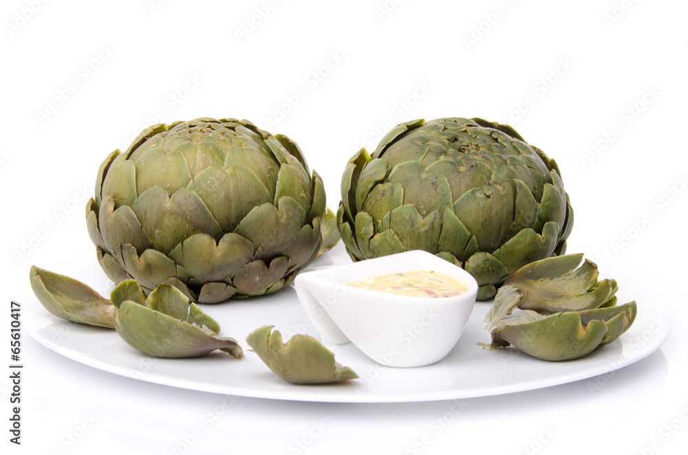 Obraz premium Cooked artichoke with a vinaigrette sauce on a plate