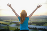 happy young woman outdoor rising hands and looking at sunset