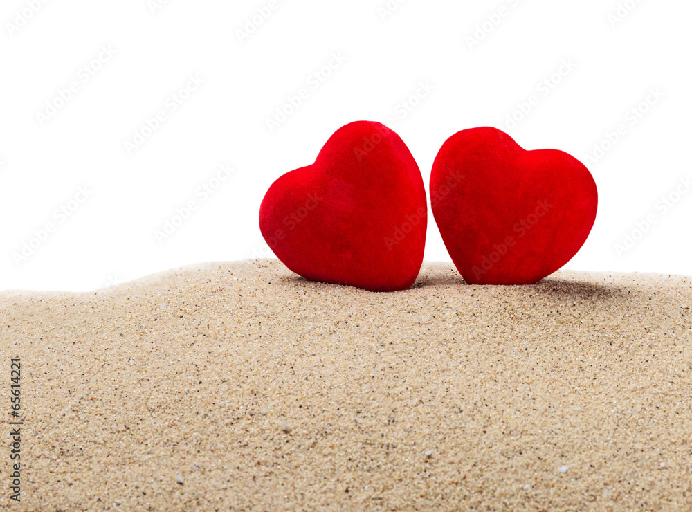 two red hearts in the sand on a white two red hearts in the sand on a white