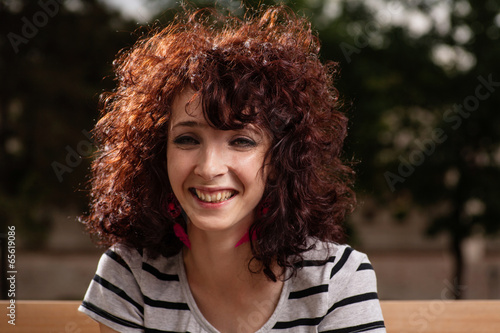 Portrait of beautiful smiling girl with curly red hair close up