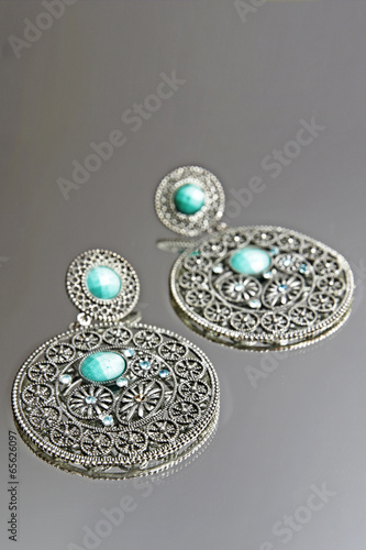 Silver earrings on grey background.