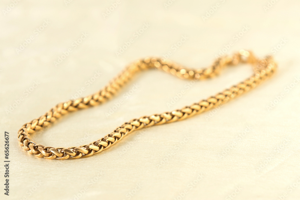 Fototapeta premium Golden necklace on the white textile.