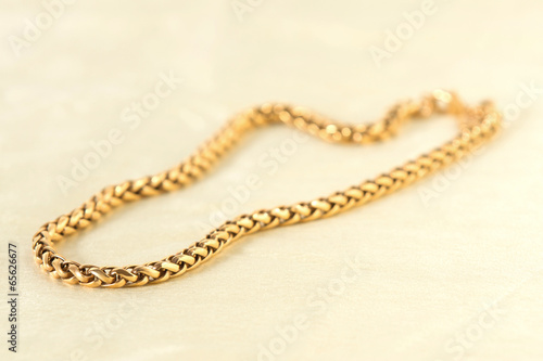 Golden necklace on the white textile.