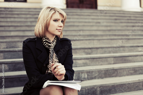 Young business woman with notebook sitting on the steps